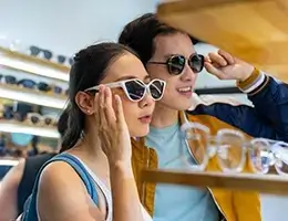 two young adult trying on sunglasses